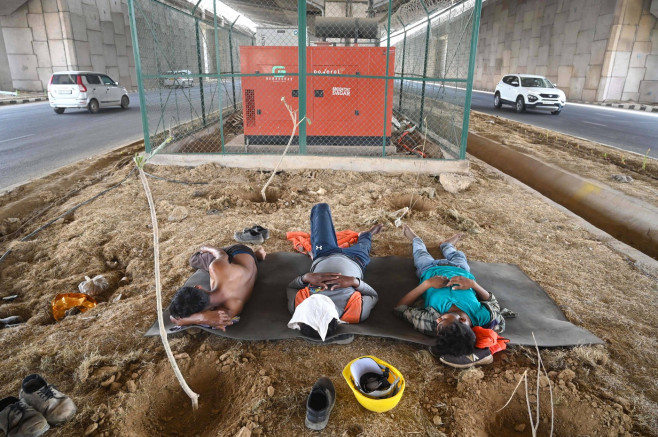 GURUGRAM, INDIA - MAY 29: Construction workers take rest during the lunch break under a flyover on a hot summer day at D