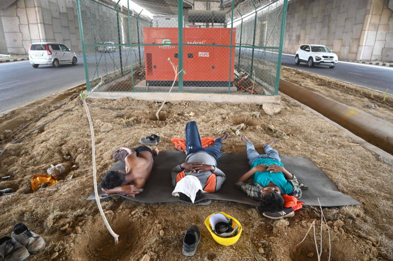 GURUGRAM, INDIA - MAY 29: Construction workers take rest during the lunch break under a flyover on a hot summer day at D