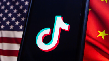 Vancouver, CANADA - Apr 30 2024 : TikTok logo seen in an iPhone screen on American flag and Chinese flag background