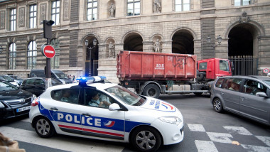 A police car filled with police going down a street in Paris, France