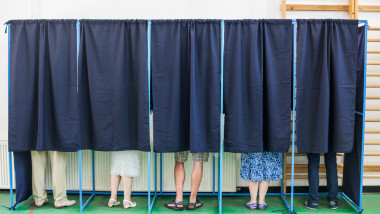 mai multe persoane voteaza in cabine de vot