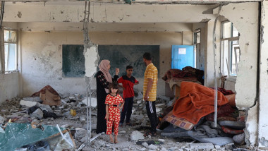 Members of a displaced family look at the damage to a school run by the UN Relief and Works Agency for Palestine Refugees (UNRWA) which was hit during an Israeli army strike
