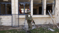 soldat israelian lângă o clădire cu geamuri sparte