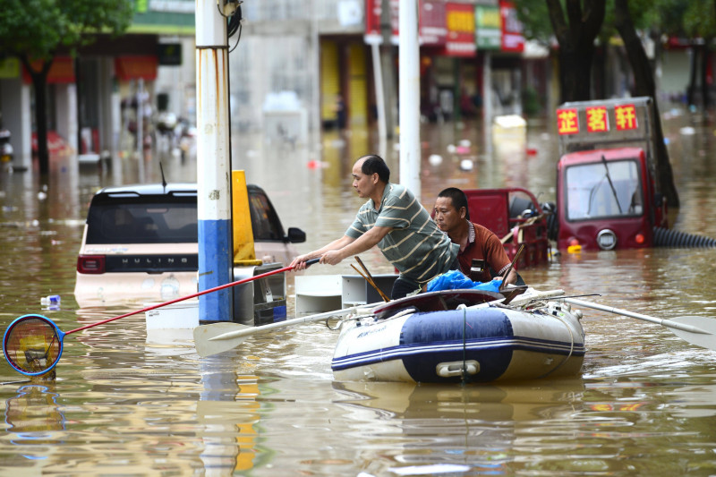 HEZHOU, CHINA - JUNE 15: A citizen cleans a waterlogged road on an inflatable boat after a heavy rainfall on June 15, 20