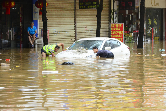 HEZHOU, CHINA - JUNE 15: A citizen transfers a car half-submerged in a waterlogged road after a heavy rainfall on June 1