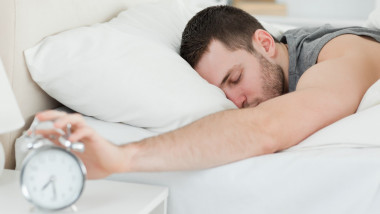 Sleeping man being awakened by an alarm clock