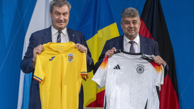 Prim-ministrul Bavariei Markus Söder tine in mana un tricou al nationalei de fotbal a romaniei și premierul Marcel Ciolacu tine in mana un tricoul al echipei nationale de fotbal a germaniei