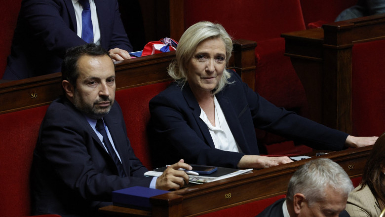 President of the "Rassemblement National" (RN) group at the National Assembly Marine Le Pen (C) looks on flanked by French MP for the "Rassemblement National" (RN) Sebastien Chenu (L), during a session of questions to the government at the National Assembly in Paris