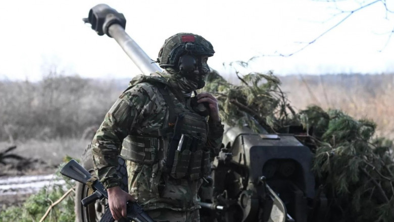 un soldat în Ucraina lângă un sistem de artilerie