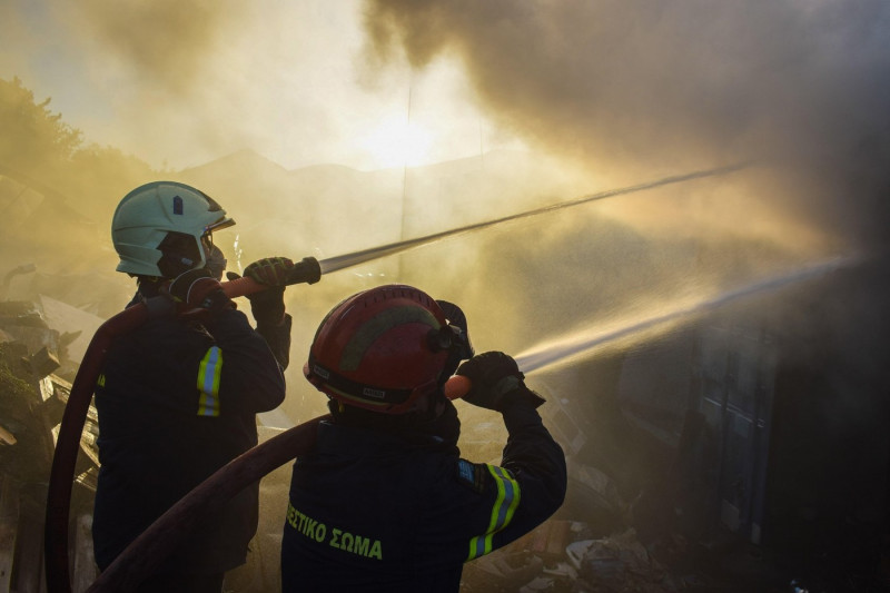 Athens, Greece. 19 June 2024. Firefighters attempt to extinguish a fire amidst thick smoke that has broke out in a factory area during a wildfire in the eastern suburbs of the Greek capital. Authorities have urged residents to evacuate an area on the frin