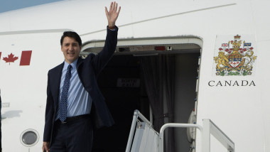 Premierul Canadei Justin Trudeau face cu mâna de pe scara avionului