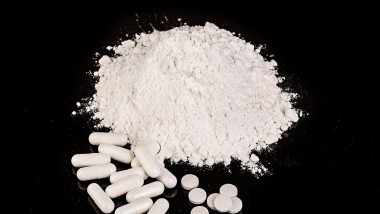 drug powder tablets and capsules close-up on black background.