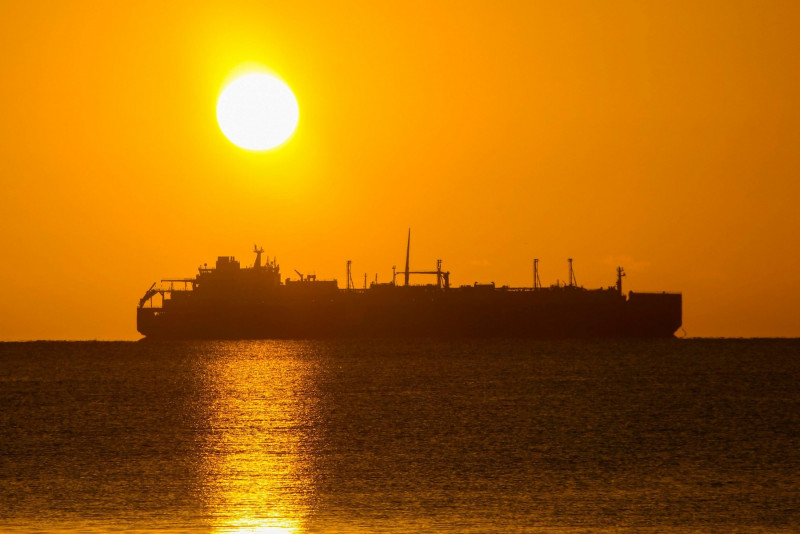 Weymouth, Dorset, UK. 20th January 2022. UK Weather. The sun rises up from behind the Yakov Gakkel an LNG tanker which is anchored in the bay at Weymouth in Dorset on a morning of clear skies. Picture Credit: Graham Hunt/Alamy Live News
