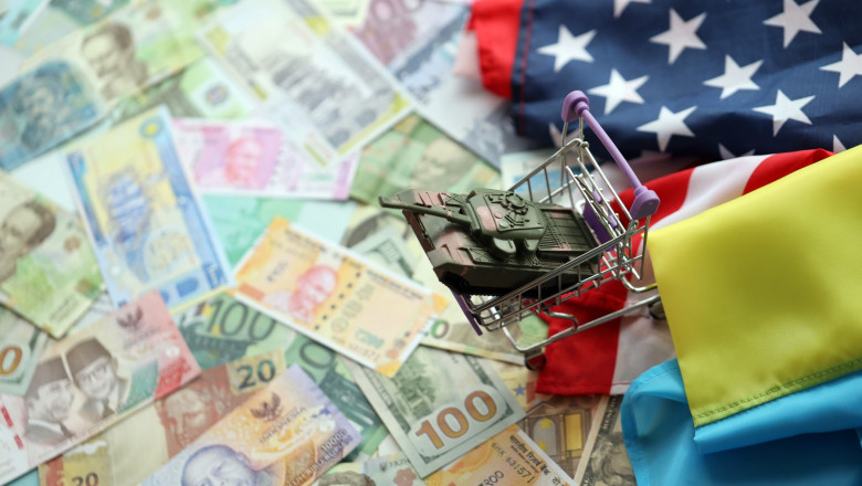 Toy tank on US flag and ukrainian flag on many banknotes of different currency