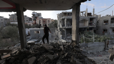 un bărbat privește ruinele unor clădiri din Gaza