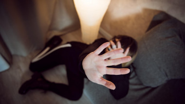 Unarmed young woman at home hand against camera protecting herself from sexual harassment high angle view