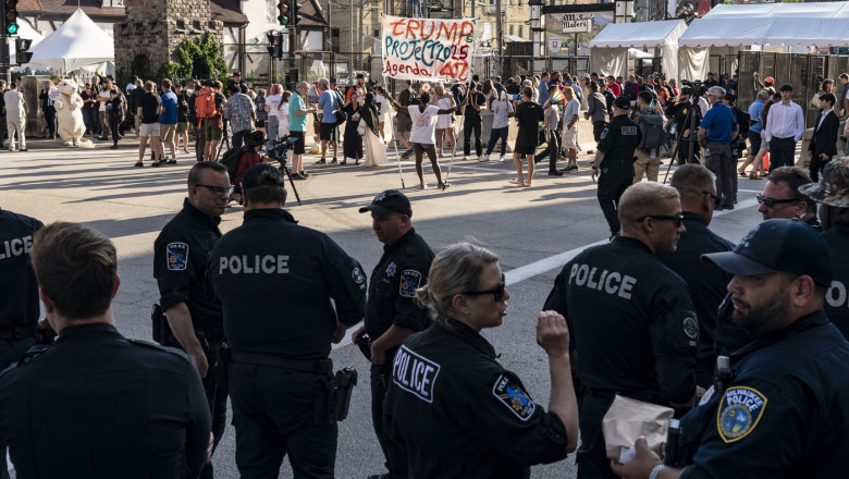 polițiști în fața unor protestatari cu pancarte anti trump