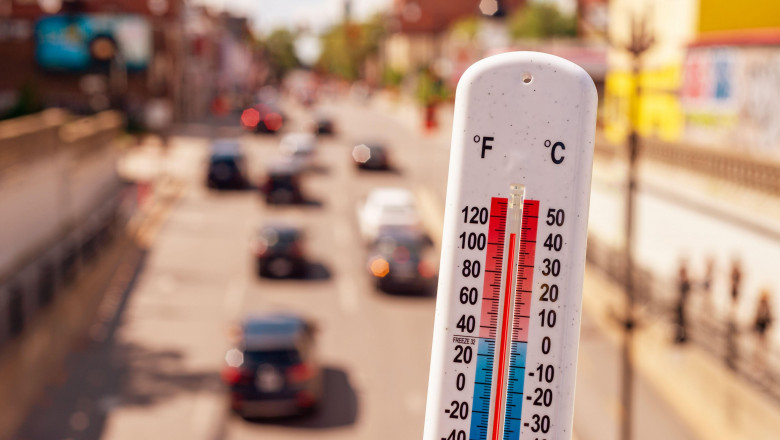 Thermometer in front of cars and traffic during heatwave in Montreal.