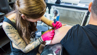 Tattoo studio, tattoo artist at work, tattooing with a machine, needle prick ink into skin