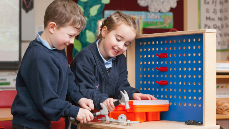 Pupils in school uniform at a Primary School in the UK playing with toy hand tools.