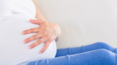 Close up of pregnant woman with one hand on belly