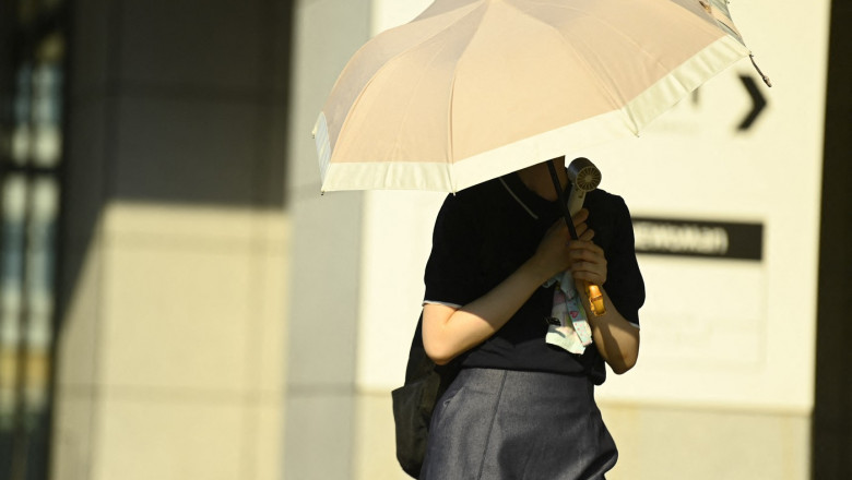 femeie cu umbrelă și ventiltor pe stradă în japonia