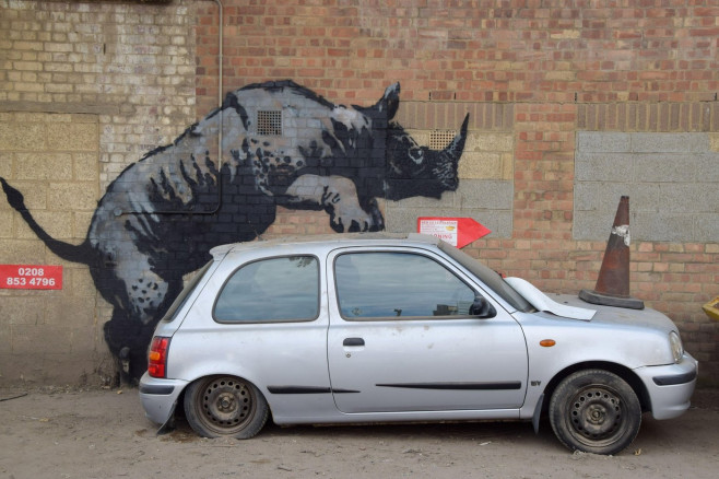 London, UK. 12th Aug, 2024. A new artwork by Banksy appears on a wall in Charlton, depicting a rhino getting intimate with a car with a traffic cone on its hood. This is the 8th new animal-themed artwork in eight days in the capital by the elusive street