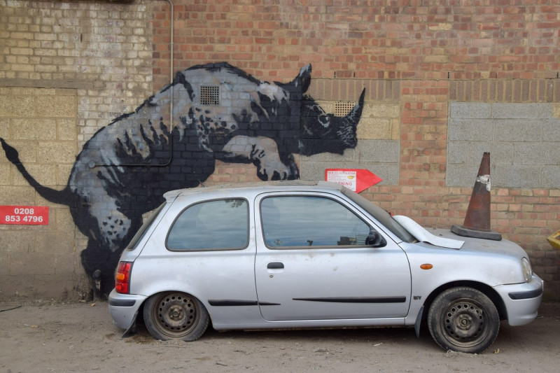 London, UK. 12th Aug, 2024. A new artwork by Banksy appears on a wall in Charlton, depicting a rhino getting intimate with a car with a traffic cone on its hood. This is the 8th new animal-themed artwork in eight days in the capital by the elusive street