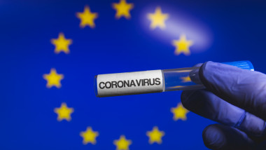 O eprubetă pe care scrie coronavirus, pe fundalul unui steag al Uniunea Europene