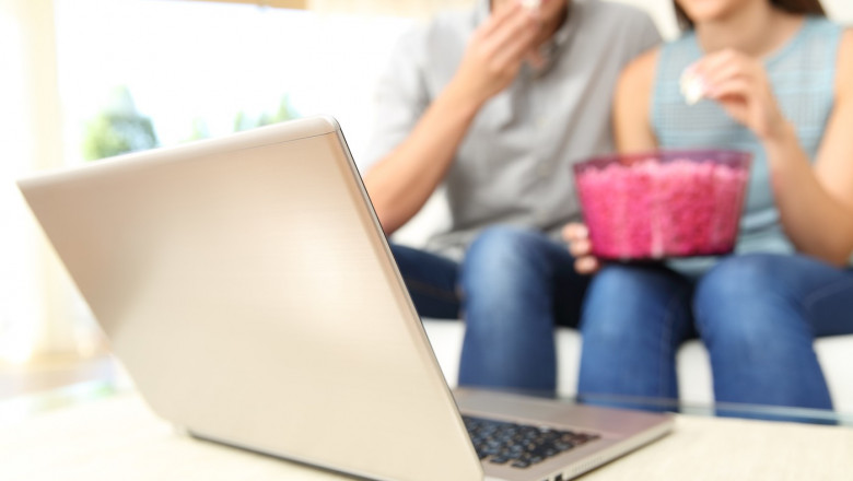 Couple watching online tv movie on laptop at home