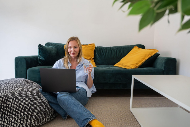 woman freelancer working on laptop and drinks water from a glass