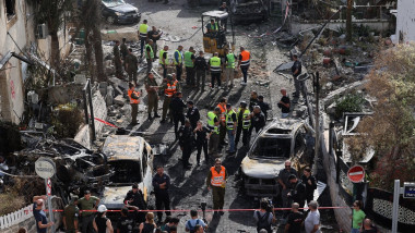 Residents watch as first responders and Israeli security forces gather amid debris and charred vehicles in Kiryat Bialik in the Haifa district of Israel, following a reported strike by Lebanon's Hezbollah on September 22, 2024