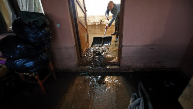 un om scoate apa din casa afectata de inundatii