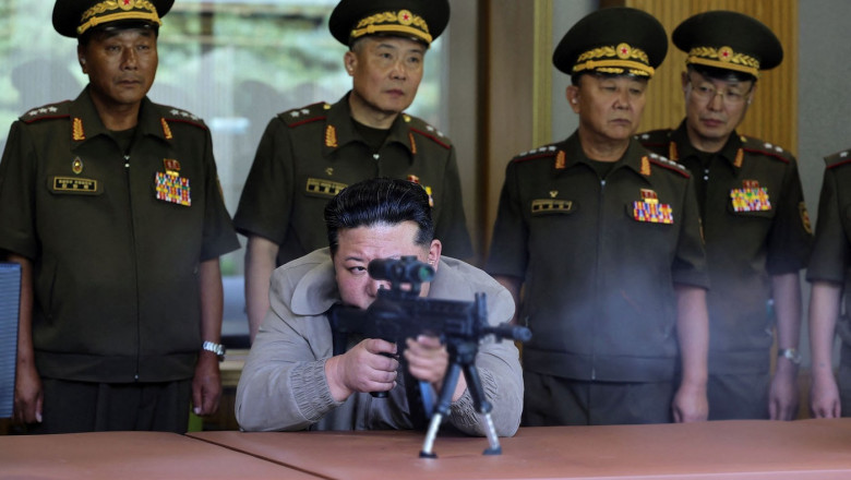 Kim Jong Un (C) test-firing a sniper weapon developed by the Academy of Defence Sciences