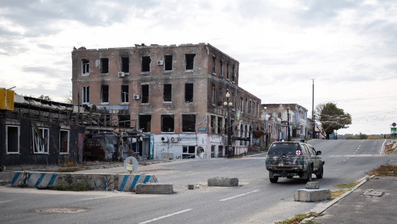 A military vehicle drives through a roadblock near destroyed buildings in Kupyansk