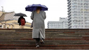 Woman,With,Umbrella,Walking,Up,The,Steps,On,City,Buildings