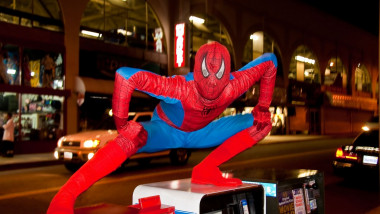 Spider Man movie character impersonator striking a pose atop newspaper vending machines on Hollywood Blvd