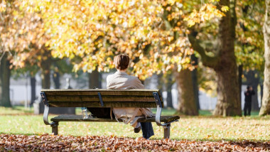 ub barbat sta pe o banca in parc