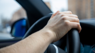 Unrecognizable,Person,Holds,Her,Right,Hand,On,The,Steering,Wheel