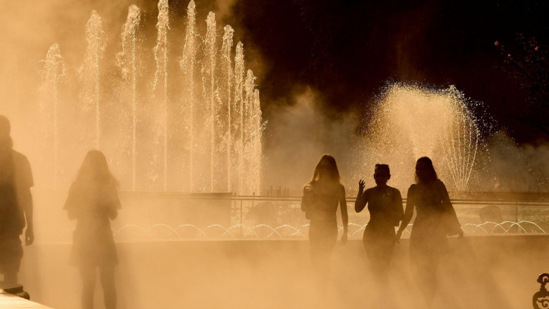 Bucharest, Romania. 22nd July, 2024: People walk through the fine spray of a fountain on a very hot day. Credit: Lucian Alecu/Alamy Live News