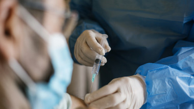 Doctor injecting covid-19 vaccine to senior man at his home.