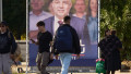 Bucharest, Romania. 1st Oct, 2024: People walk past a large banner from the presidential election campaign of Marcel Ciolacu, president of Social Democratic Party (PSD) and Romanian prime minister. Credit: Lucian Alecu/Alamy Live New