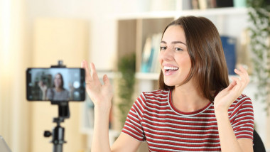 Happy influencer recording video with a smart phone at home