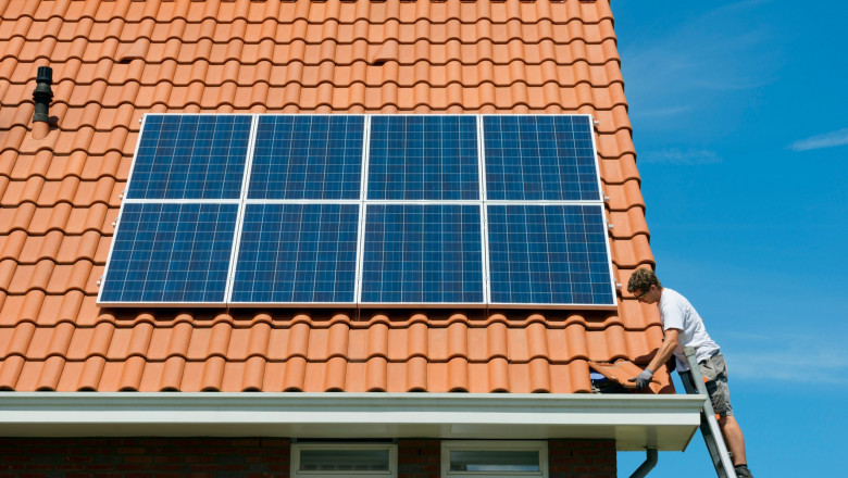 un barbat monteaza panouri fotovoltaice pe o casa