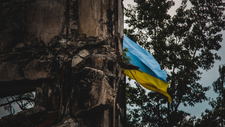 A,Ukrainian,Flag,Waves,In,The,Background,Of,War-torn,Ruins,