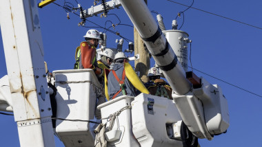 Workers replacing electrical equipment on utility pole