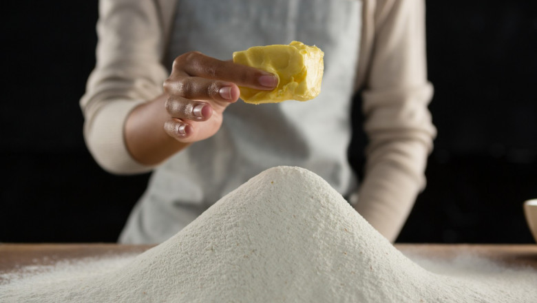 Woman adding butter cube into flour