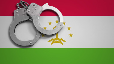 Tajikistan flag and police handcuffs. The concept of crime and offenses in the country