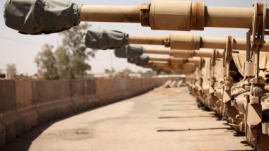 A line of M109A6 Paladins, assigned to Alpha Battery, 3rd Battalion, 82nd Field Artillery Regiment, 2nd Brigade Combat Team, 1st Cavalry Division, sit unused with covers over their 155 milimeter Howitzers, in the motor pool, on Forward Operating Base War