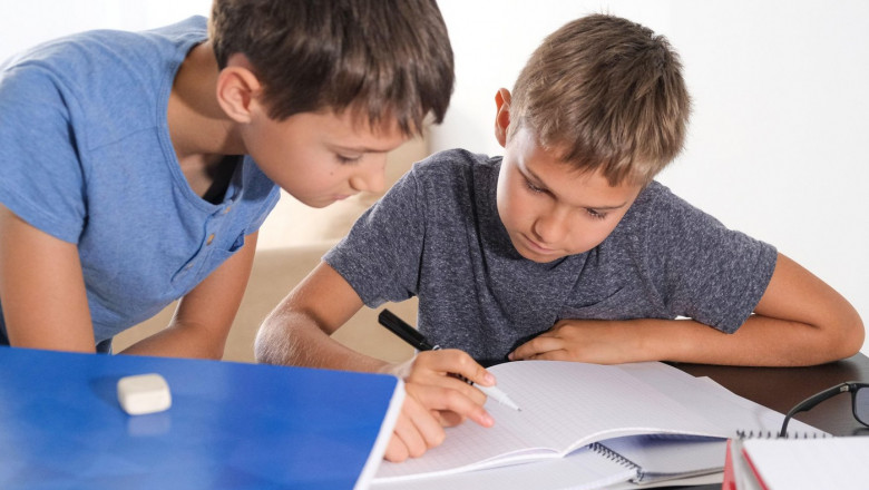 Learning at home, self quarantine concept. Children at home doing homework with books notebooks and thinking how to make math tasks